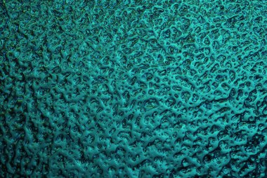 Parlak deniz mavisi kış arkaplanı. Pencere camında donmuş buzun yüzeyi. Merkür dalgalanmalarına benzer, metalik parıltılı soyut bir desen. Zengin turkuaz duvar kağıdı. Yakın plan.