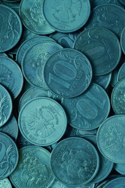 10 rublelik Rus sikkeleri. Dikey turkuaz renkli arka plan. Ekonomi ve Rusya Merkez Bankası. Para rublesi desenli arkaplan. Yakın plan.