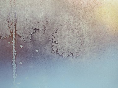 Donmuş ve sisli pencere camları. Soyut kış arkaplanı ya da duvar kağıdı. Buz kristalleri ve su damlacıkları. Güneşin battığı soğuk bir günün sonu. Mavi ve sarı doğal arkaplan