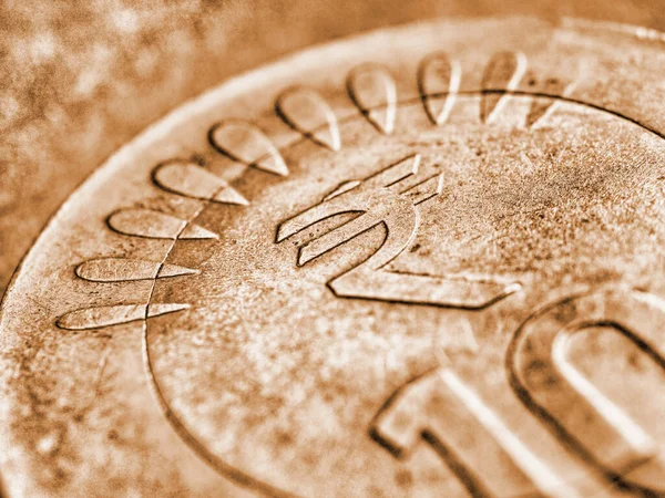 Translation: rupee. Fragment of Indian 10 rupee coin with the sign of the national currency close-up. Brown tinted background from money about economy or finances of India. Macro