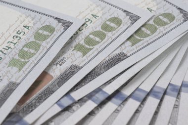 Yüz dolarlık Amerikan banknotları. Yakın plan notların bir parçası. 100 rakamına odaklan. Ekonomik para tasarrufu ve Amerikan doları. Hafif soluk arkaplan ve düşük doygunluk. Makro