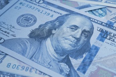 Amerikan kağıt parası. Benjamin Franklin 'in gözlerine odaklı 100 dolarlık banknot. Amerikan banknotları yakın plan. İş ekonomisi ve Amerikan doları. Mavi renkli arka plan. Makro