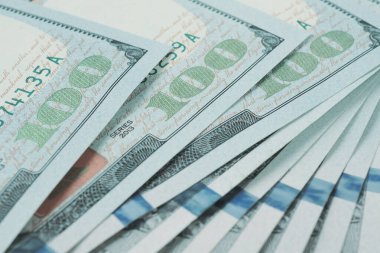 Yüz dolarlık Amerikan banknotları. Yakın plan notların bir parçası. 100 rakamına odaklan. Ekonomik para tasarrufu ve Amerikan doları. Hafif soluk arkaplan ve düşük doygunluk. Makro