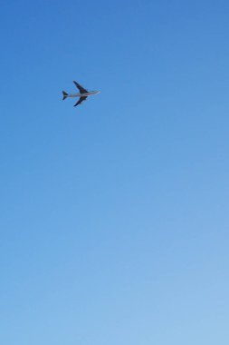 Büyük dört motorlu nakliye uçağı mavi gökyüzünde çok uzaklara uçuyor. Uluslararası hava taşımacılığı hakkında dikey çizim