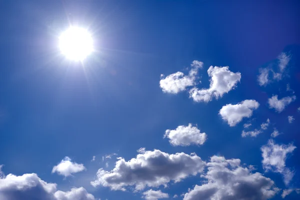 De felle zon schijnt wolken in de blauwe hemel — Stockfoto