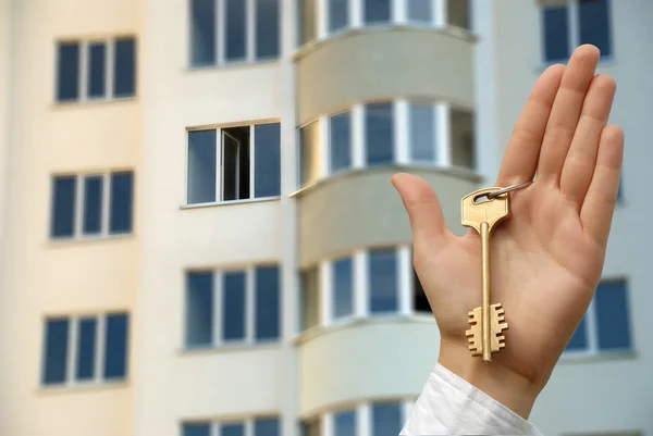 Kauf einer neuen Wohnung. die Hand hält einen Schlüssel hoch. — Stockfoto