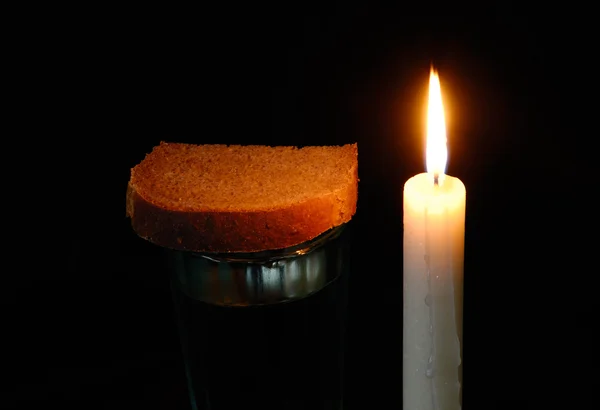 Burning candle, a glass with water and breads — Stock Photo, Image