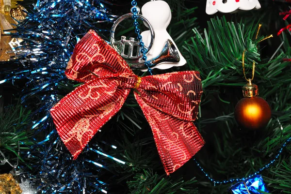 Red bow knot hanging on fir tree — Stock Photo, Image