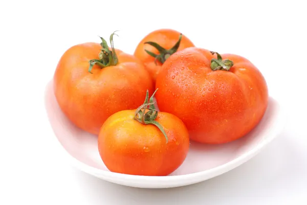 Cuatro tomates en un plato —  Fotos de Stock