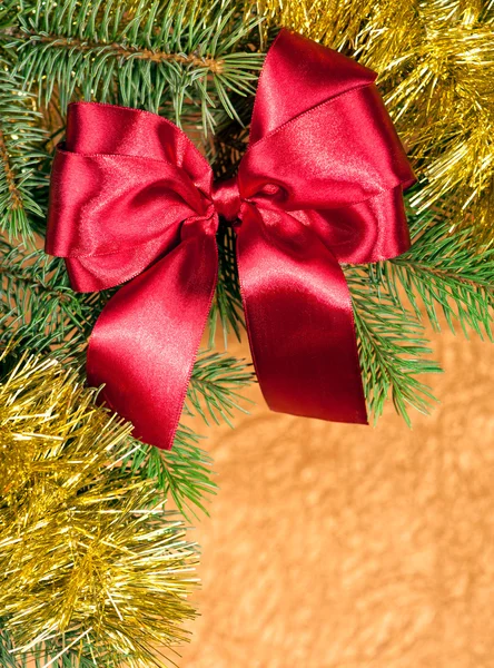 Fir branches with red bow on golden background — Stock Photo, Image