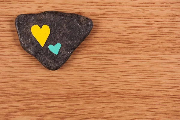 Corazones sobre piedra y fondo de madera — Foto de Stock