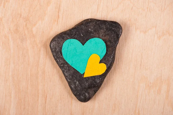 Corazones sobre piedra y fondo de madera — Foto de Stock