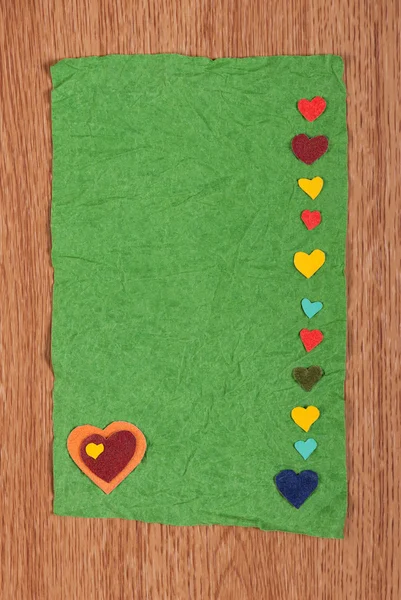 Карточка из скомканной бумаги и набор сердец на деревянном фоне — стоковое фото