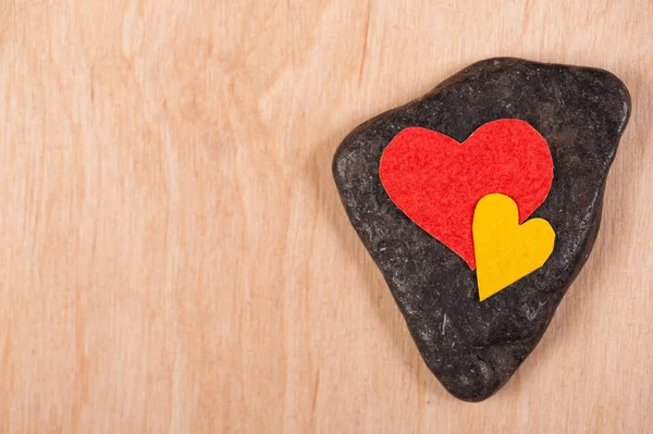 Corazones sobre piedra y fondo de madera — Foto de Stock