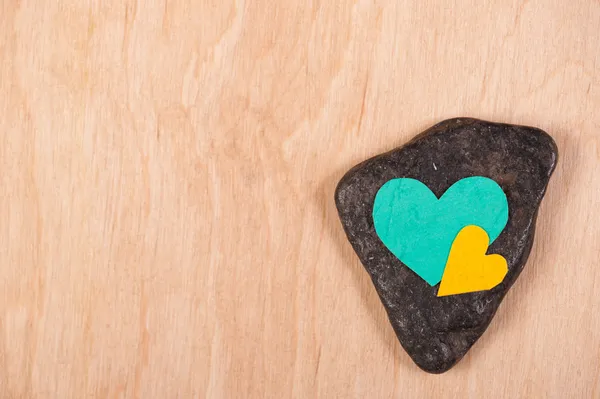 Corazones sobre piedra y fondo de madera — Foto de Stock