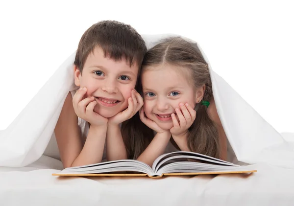 孩子们读一本书躺在床上 — 图库照片