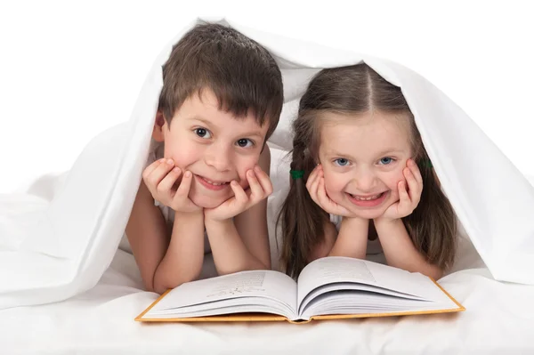 孩子们读一本书躺在床上 — 图库照片