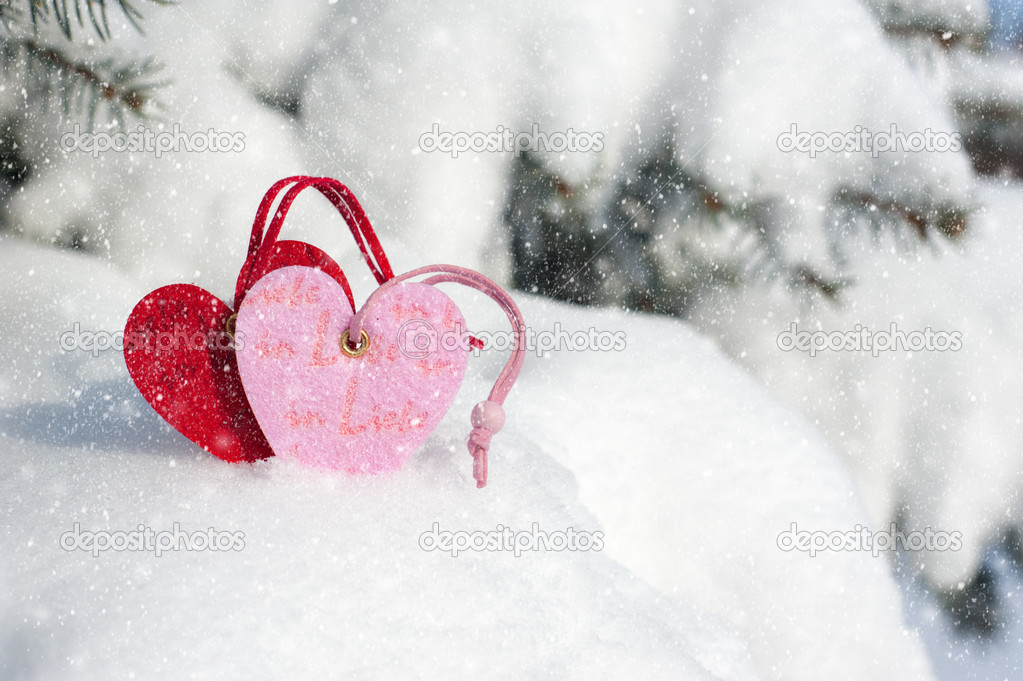 red heart toy in snowfall on fir tree