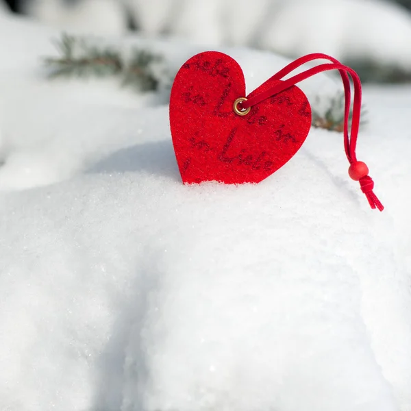 Brinquedo coração vermelho na neve no abeto — Fotografia de Stock