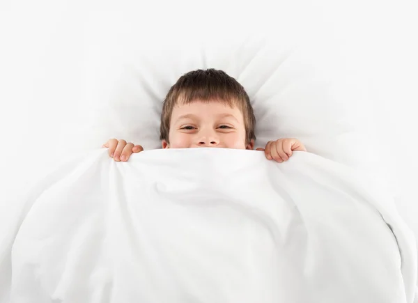 Fröhlicher Junge im weißen Bett — Stockfoto