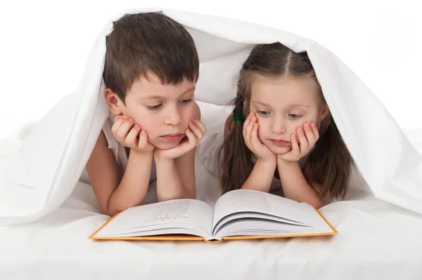 Bambini leggere un libro a letto sotto la coperta — Foto Stock