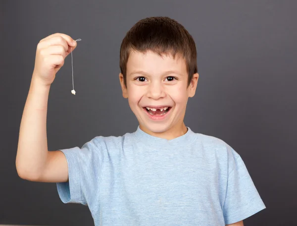 Çocuğa bir iş parçacığı üzerinde kayıp diş göster — Stok fotoğraf