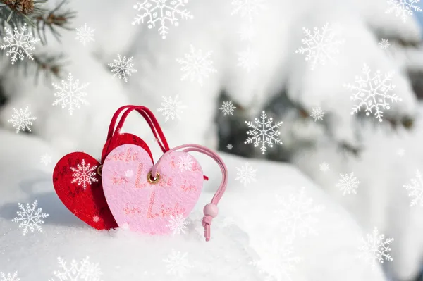 Red hearts toy in snowfall on fir tree — Stock Photo, Image