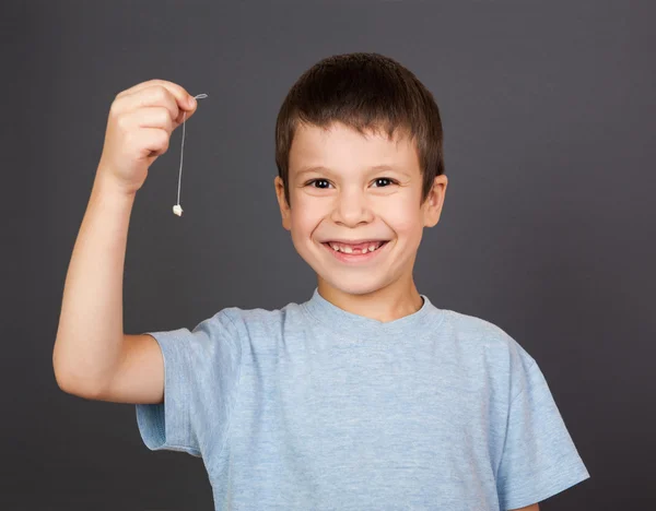Çocuğa bir iş parçacığı üzerinde kayıp diş göster — Stok fotoğraf