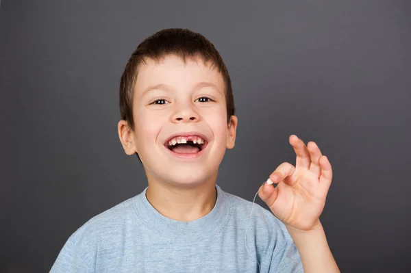 Junge zeigt verlorenen Zahn am Faden — Stockfoto