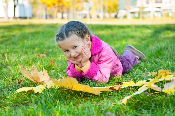 Fille se trouve sur l'herbe dans le parc d'automne — Photo