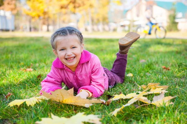 Meisje ligt op gras in herfst park — Stockfoto
