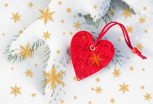 Red heart toy in snowfall on fir tree Stock Image