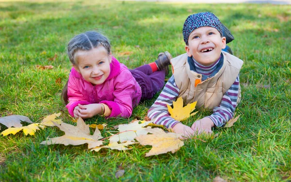 Kind liegt im Herbstpark auf Gras — Stockfoto