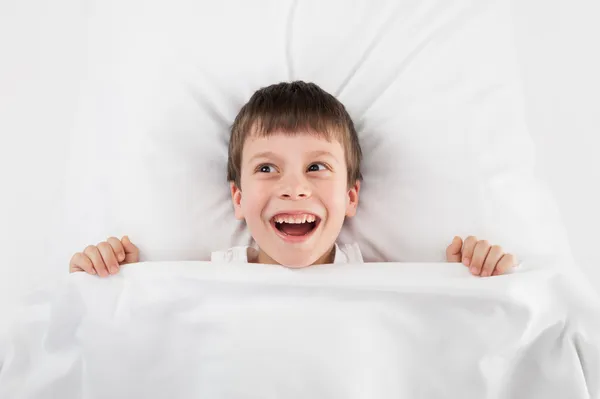 Cheerful boy in white bed — Stok fotoğraf