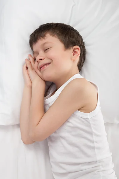 Fröhlicher Junge schläft im weißen Bett — Stockfoto