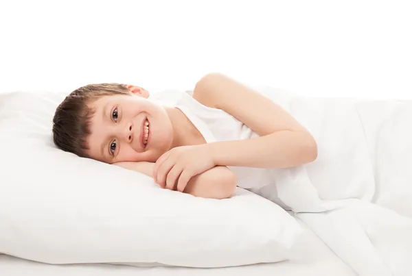 Fröhlicher Junge im weißen Bett — Stockfoto