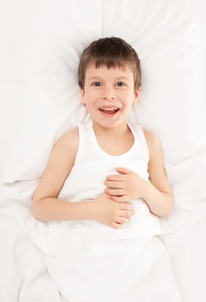 Веселий хлопчик у білому ліжку — стокове фото