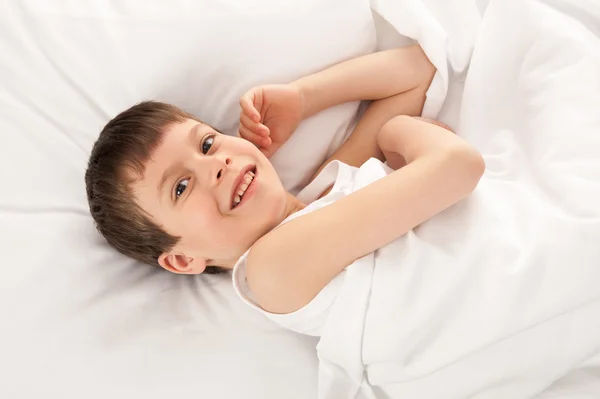 Menino alegre na cama branca — Fotografia de Stock