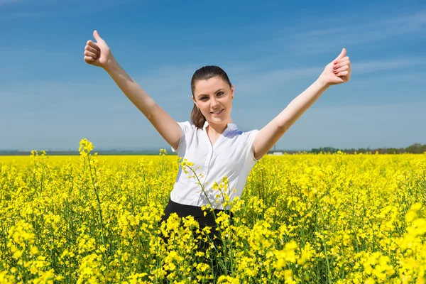 Ragazza in giacca e cravatta al campo di fiori gialli mostra miglior gesto — Foto Stock