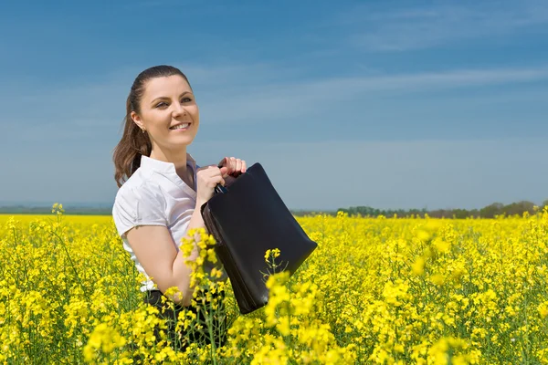 Ragazza con una valigetta sul campo di fiori gialli — Foto Stock