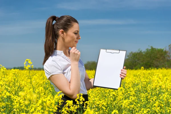 Girl with a blank paper file on yellow flower field — Stock Photo, Image