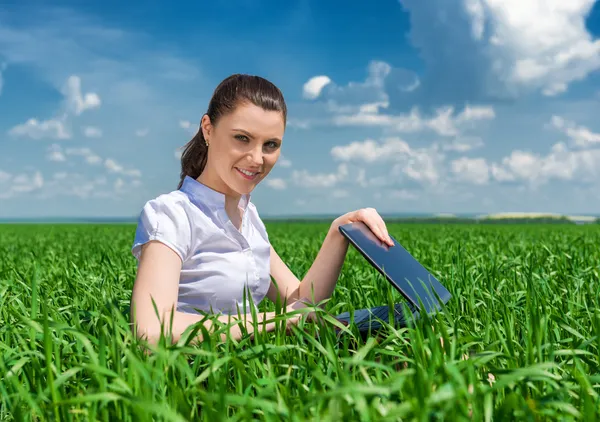 Menina com notebook no campo verde — Fotografia de Stock