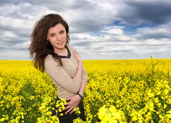 Flicka stående på gul blomma område — Stockfoto