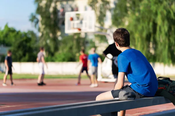 Der Kerl Sitzt Spielfeldrand Und Schaut Sich Ein Basketballspiel — Stockfoto