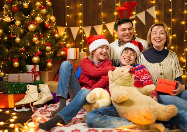 家人在新年或圣诞节装扮 孩子和父母 节日灯具和礼物 带有照明的木制背景 圣诞树上装饰着玩具 — 图库照片