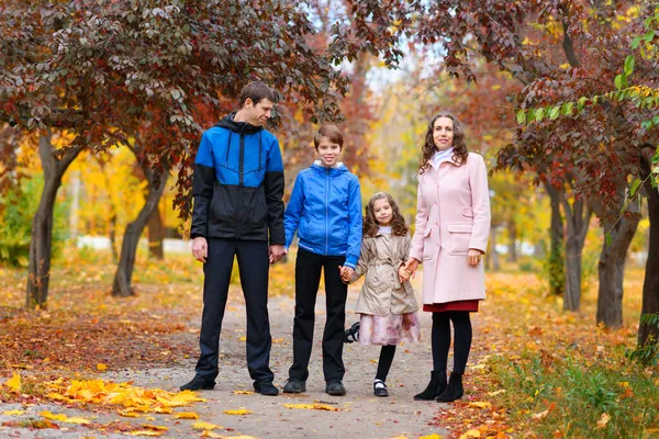 一家人沿着小路在秋天的公园里散步 它们四周环绕着美丽的大自然和黄红相间的树木 — 图库照片