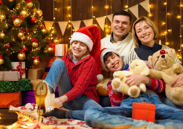 家人在新年或圣诞节装扮 孩子和父母 节日灯具和礼物 带有照明的木制背景 圣诞树上装饰着玩具 — 图库照片