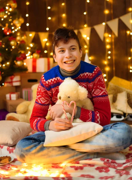 青春期男孩在新年装饰中的肖像 他吃糖果和饼干 很开心 心情也很好 节日灯饰 礼物和装饰玩具的圣诞树 — 图库照片