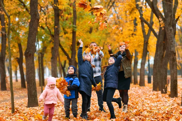 一个有孩子的家庭在秋天的城市公园里的画像 快乐的人们一起散步 他们抛掷树叶 美丽的大自然以黄叶为背景 — 图库照片