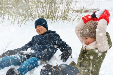 Bir kız ve bir oğlan dışarıda kartopu oynuyorlar, güzel kış havası ve beyaz kar.